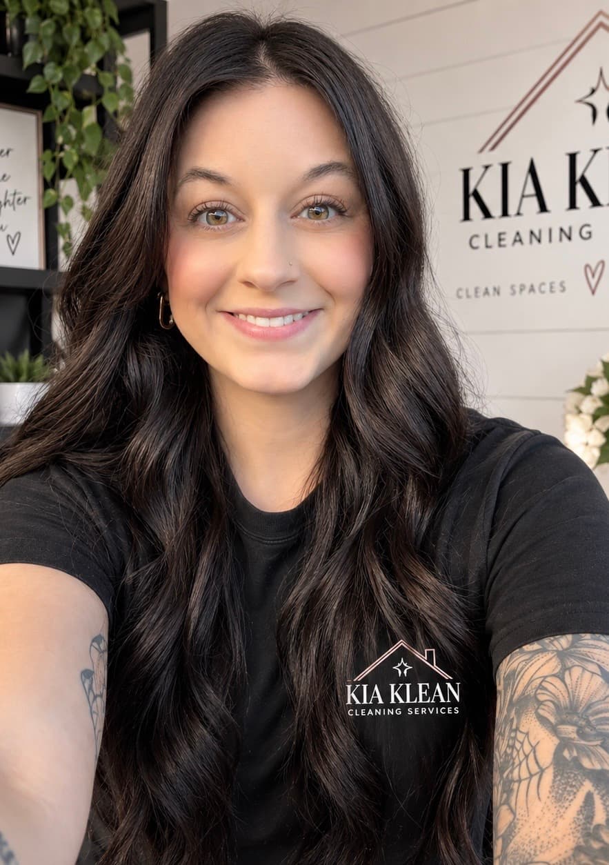 Smiling woman with long dark hair wearing a Kia Klean Cleaning Services black t-shirt.